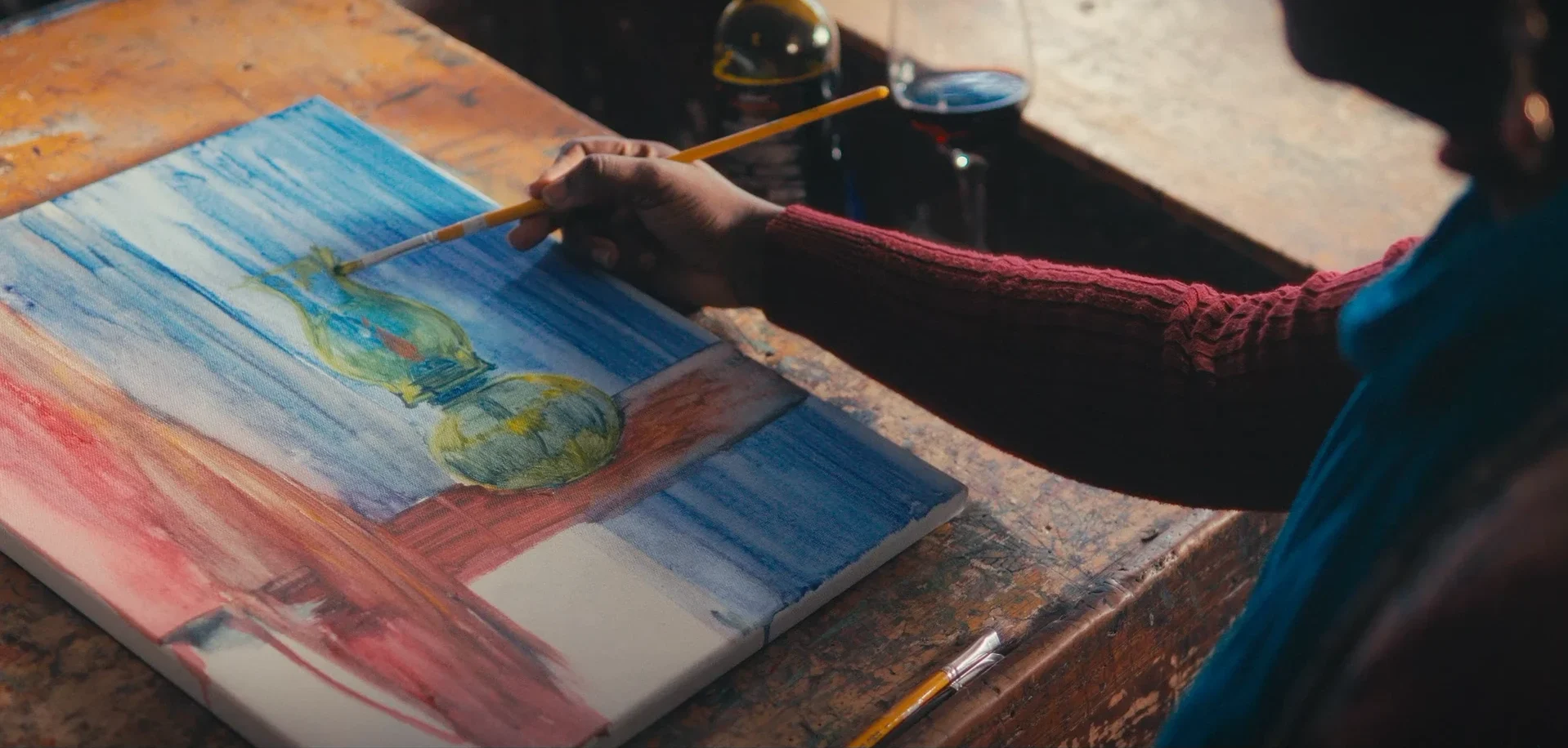 A hand paints a green vase on a blue canvas in Chiaroscurist (2024), cinematography by George Malcolm Walker