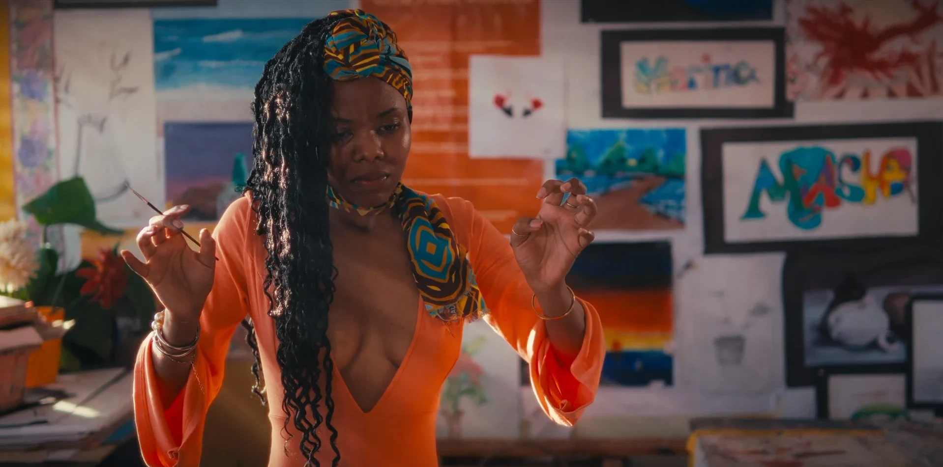 An art teacher in orange gestures with a paintbrush in her classroom in Chiaroscurist (2024), cinematography by George Malcolm Walker