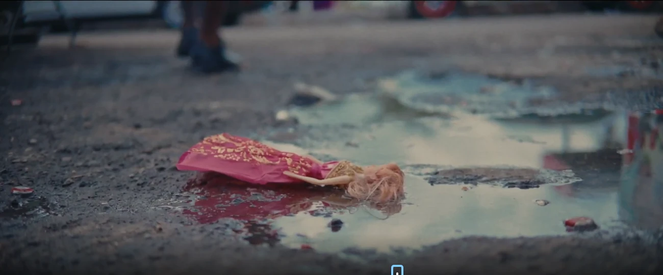 A doll in a pink dress lies face-down in a puddle in LICK, a poetic documentary by George Malcolm Walker