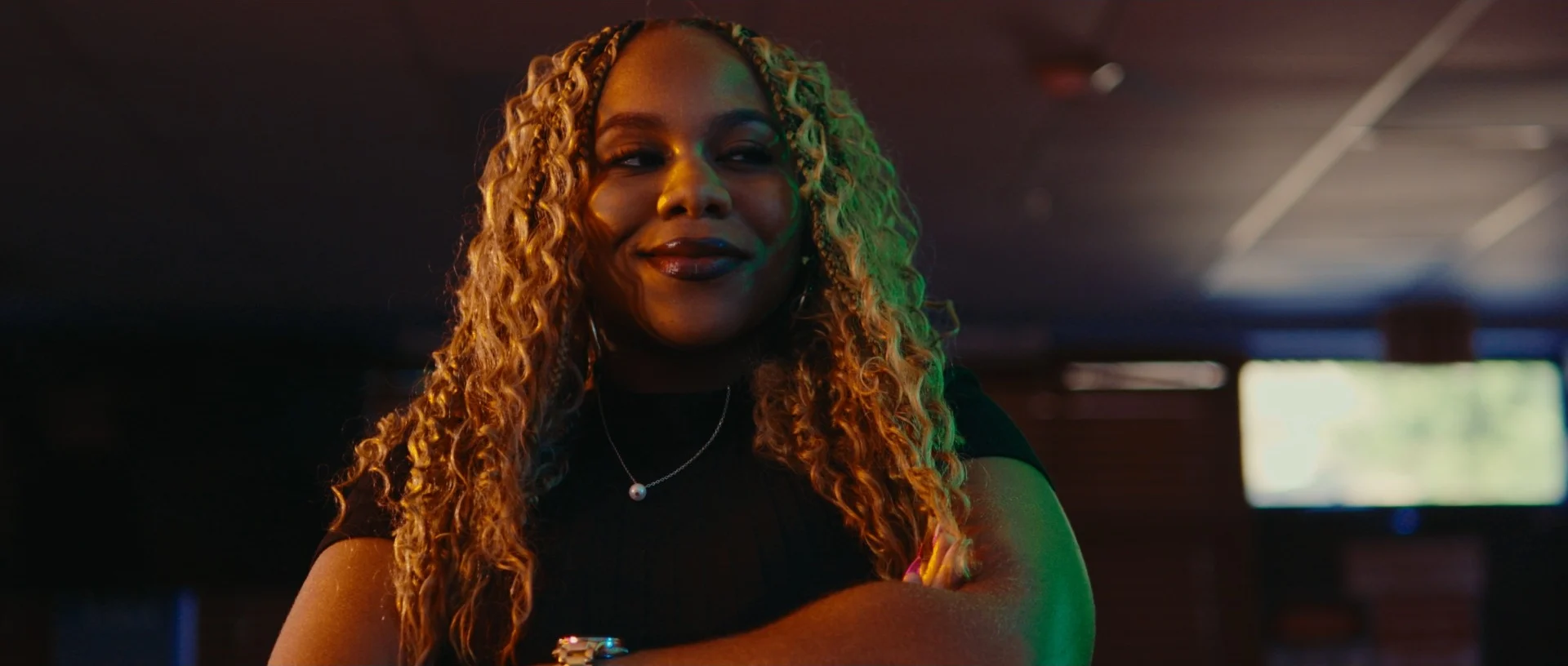 A smiling woman with curly braids, arms folded, in LUDI — a short film by Joel Miller with cinematography by George Malcolm Walker