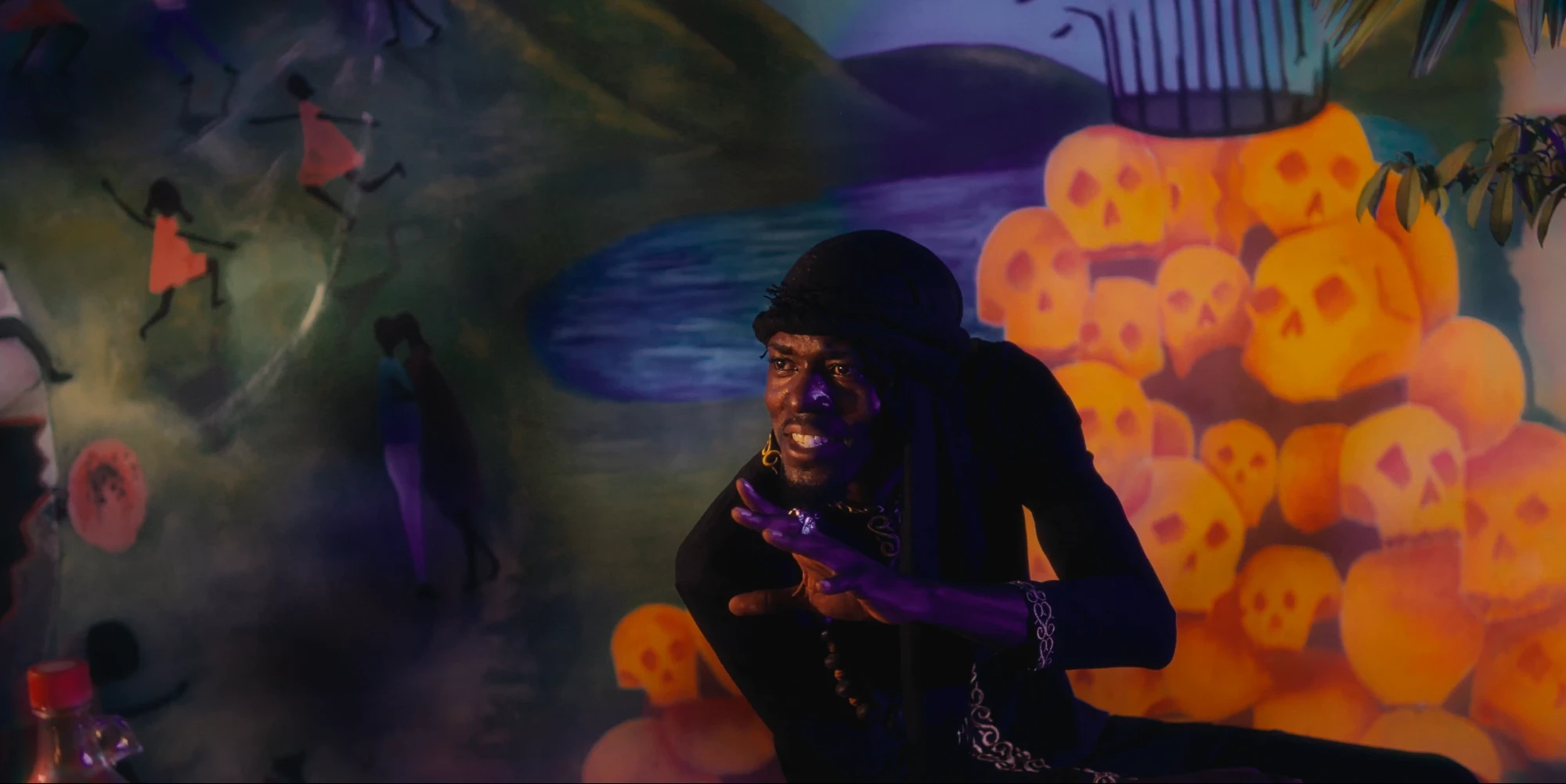 A man gestures before a painted mural of skulls in Pepper Jack (2025), cinematography by George Malcolm Walker