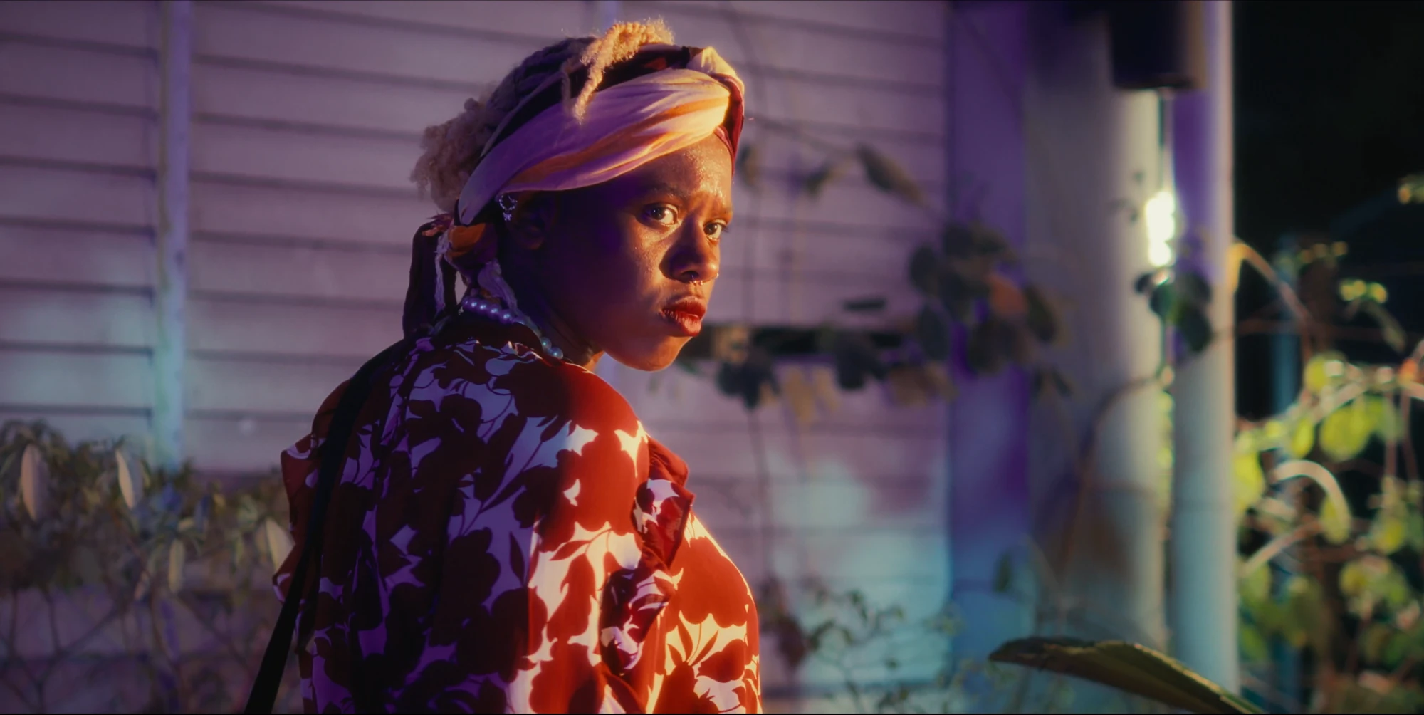 A woman in a headwrap looks back over her shoulder at night in Pepper Jack (2025), cinematography by George Malcolm Walker