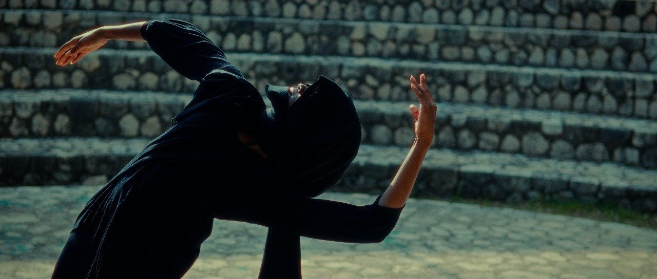 Dancer in a black hood on stone steps in the Love (Covered Me) music video — directed and shot by George Malcolm Walker